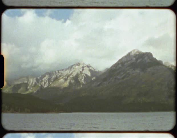Mountain slope borders rippling water under cloudy sky