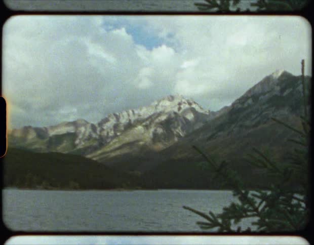 Vintage film of the peaks on a mountain range near a lake