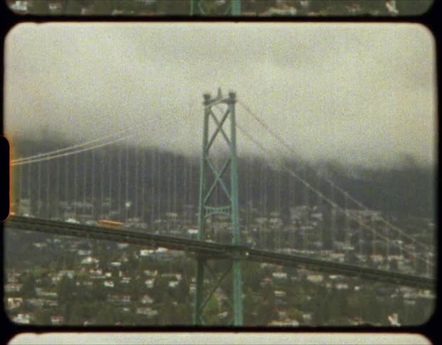 Traffic passes along a large suspension bridge over a city neighborhood