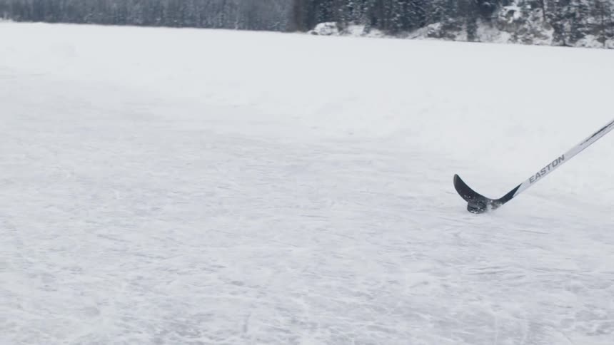 A person is ice skating pushing a puck with a stick