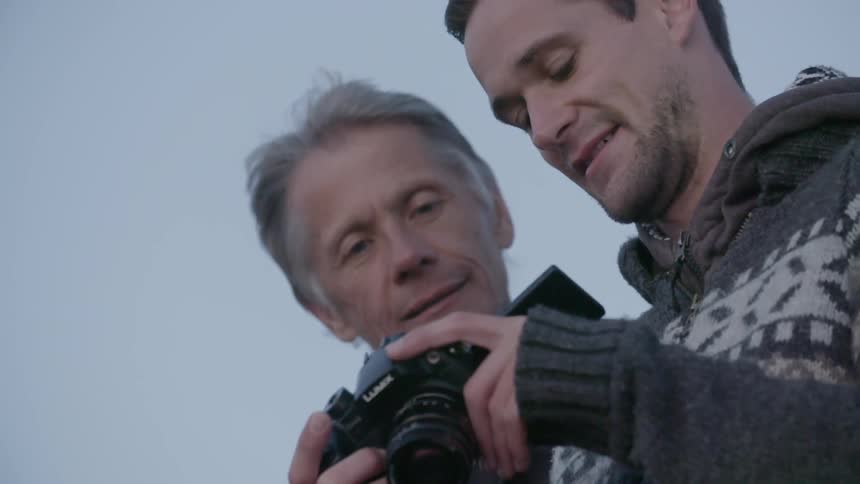 Two men looking at images on a digital camera