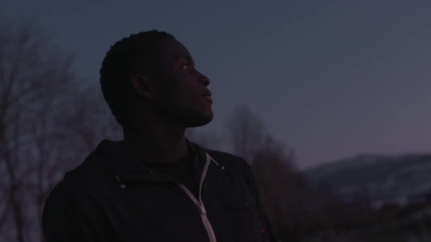 A man looking at the sky while night falls