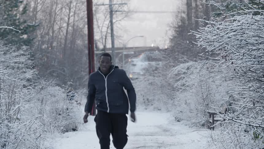 A man is running down a snow covered trail
