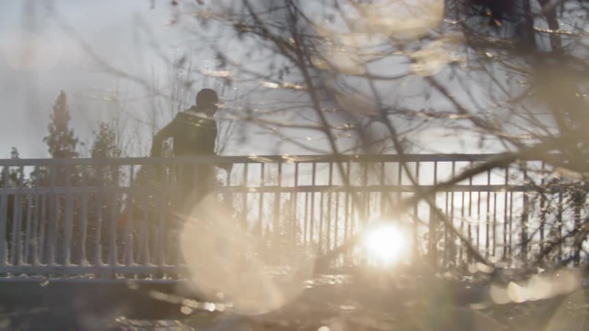 A man is running across a bridge at sunrise