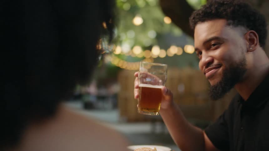 A man and woman at a restaurant clink their glasses together