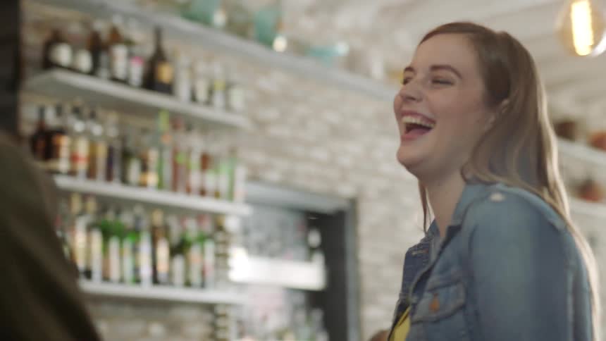 Woman sitting at a bar counter next to a man laughing