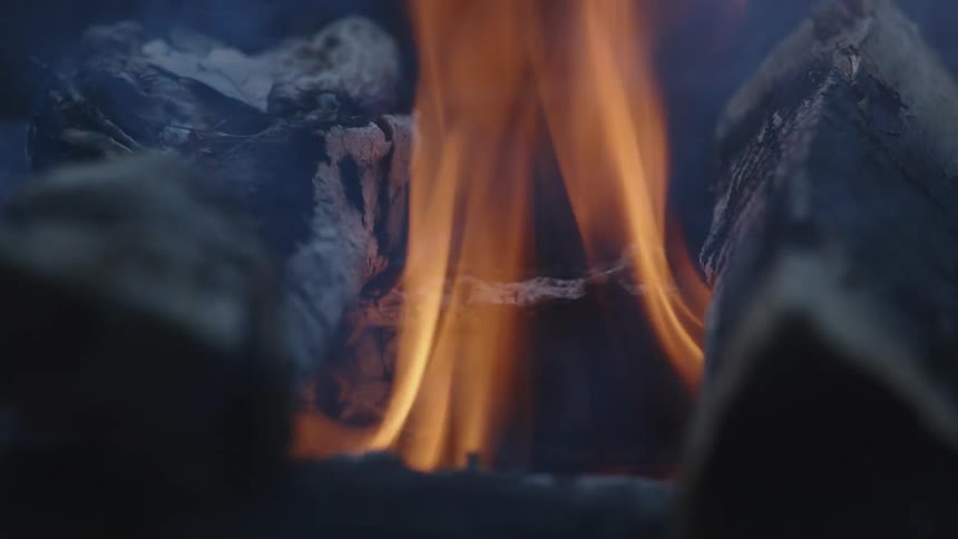 Flames dance as several pieces of wood stacked in a fire burn and smolder
