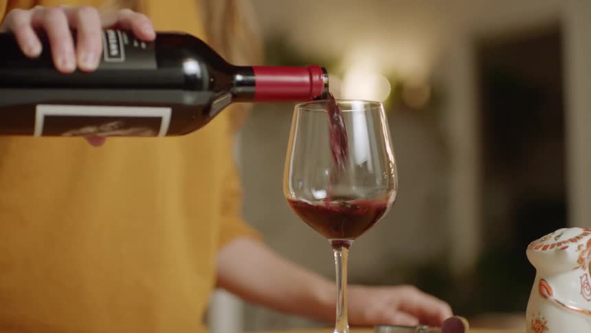Long haired blonde woman serving a glass of wine at home