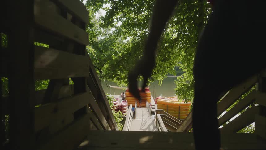 A woman is walking towards a dock that has stacks of kayaks on it