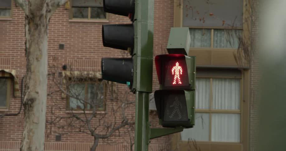 The pedestrian crossing symbol is illuminated red as a passenger bus drives past