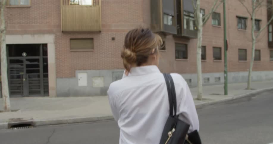 Woman walks past parked vehicle on a street and crosses the street to the other side