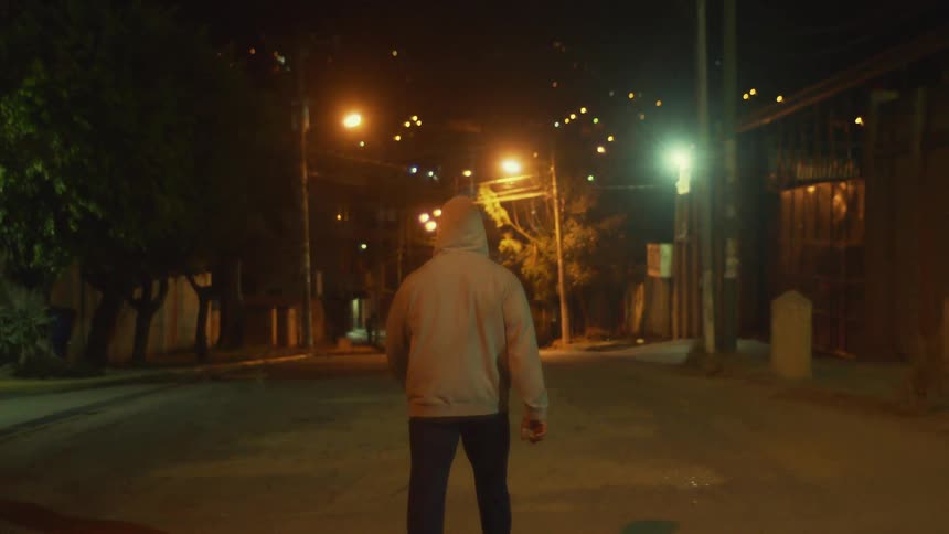 A man is walking through a city at night