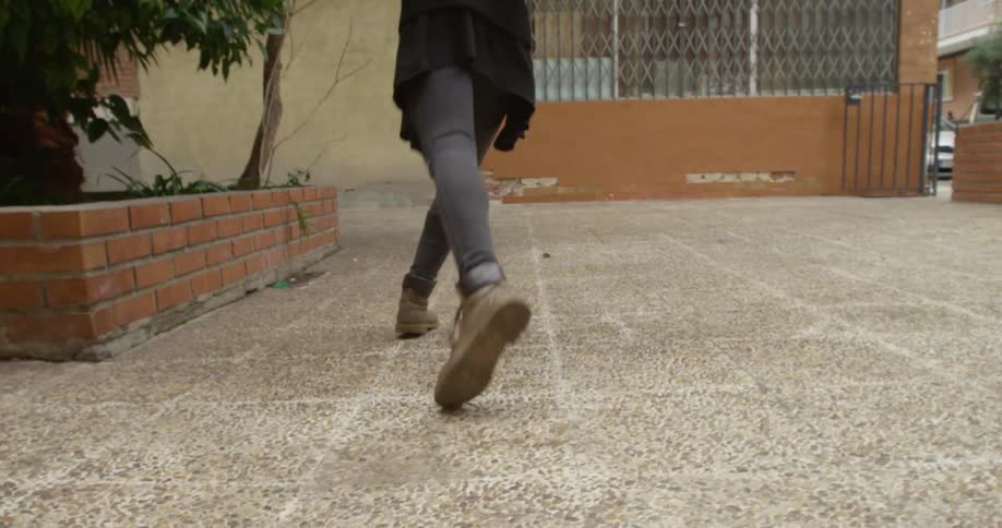 A woman is dancing outdoors in a neighborhood