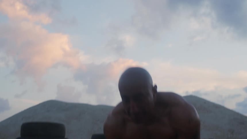 A man exercising flips tires outside