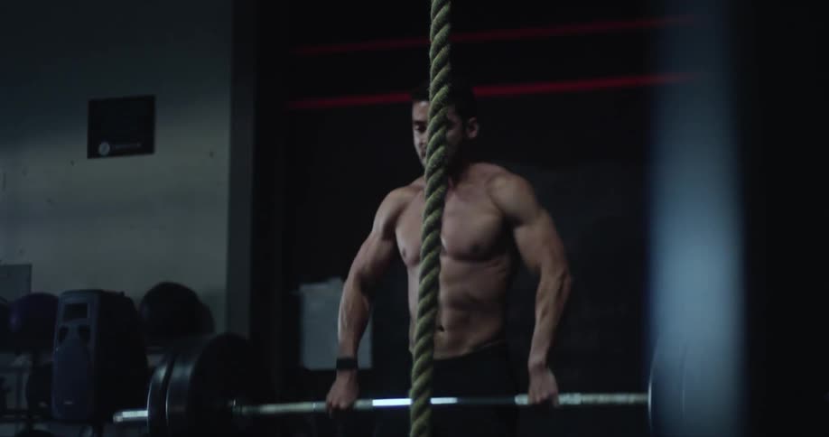 Man lifts a barbell with weight plates in a gym placing it on his shoulders and back down again