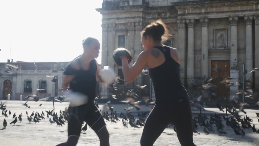 Two women are boxing outdoors