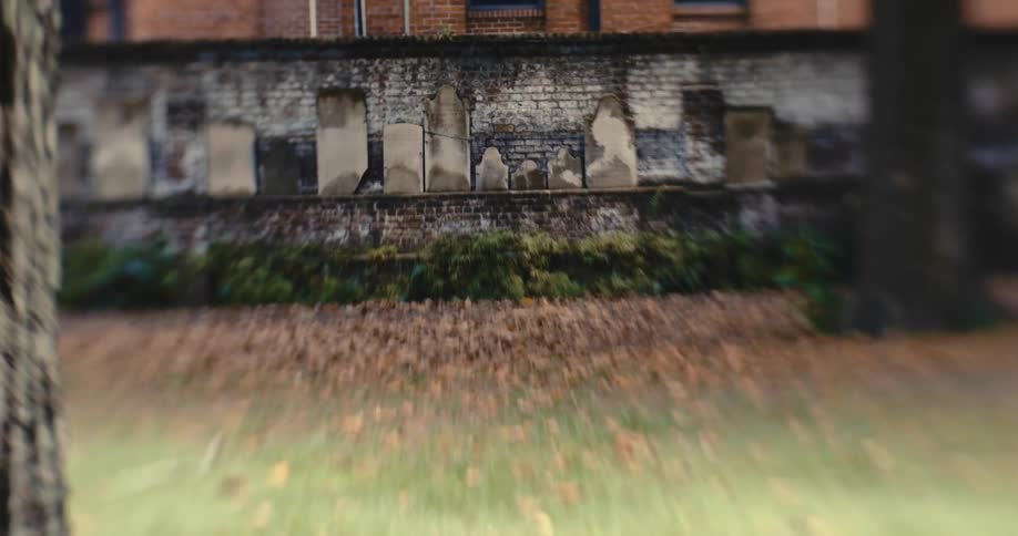 Haunted gravestones line a brick wall