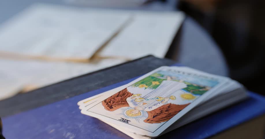 Suit of tarot cards placed over a blue book in a table