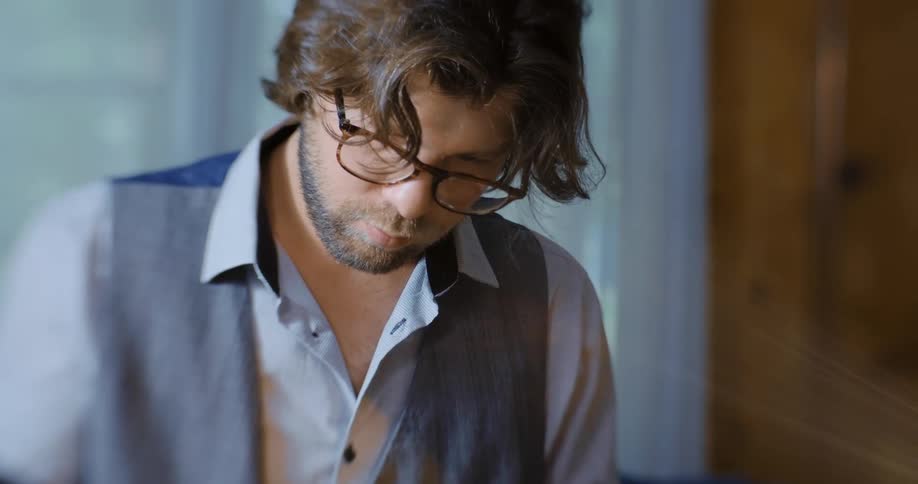 Man wearing glasses reading tarot cards over a table in a room