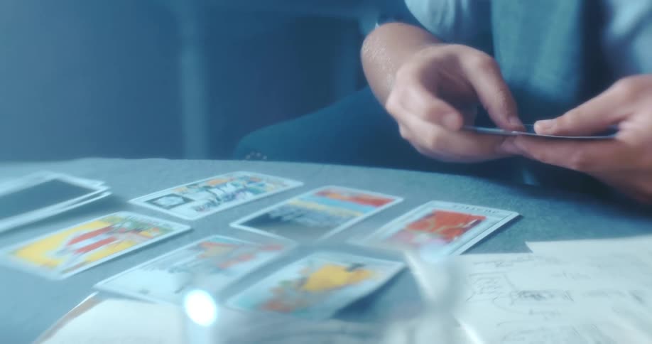 A man lays down tarot cards while sitting at a round table