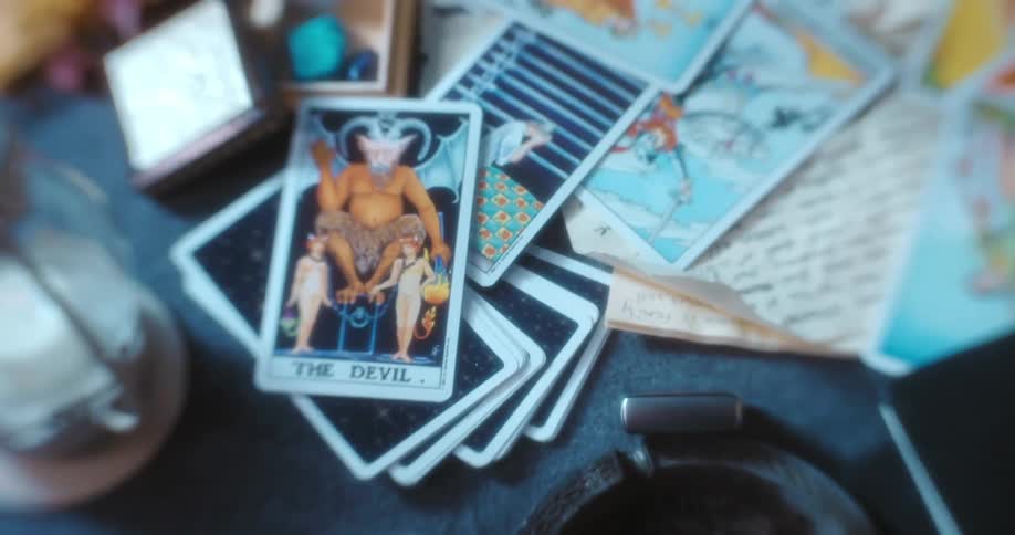 A desk with an ashtray tarot cards and candle