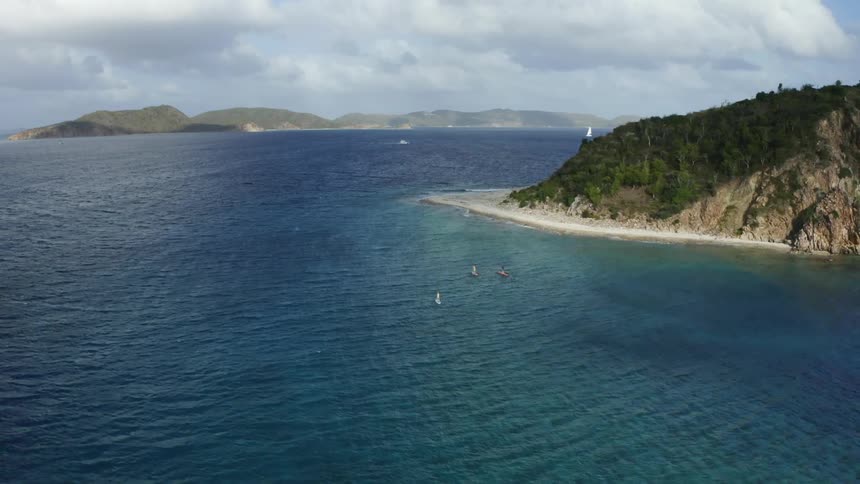 Paddleboarders paddle across a tropical bay