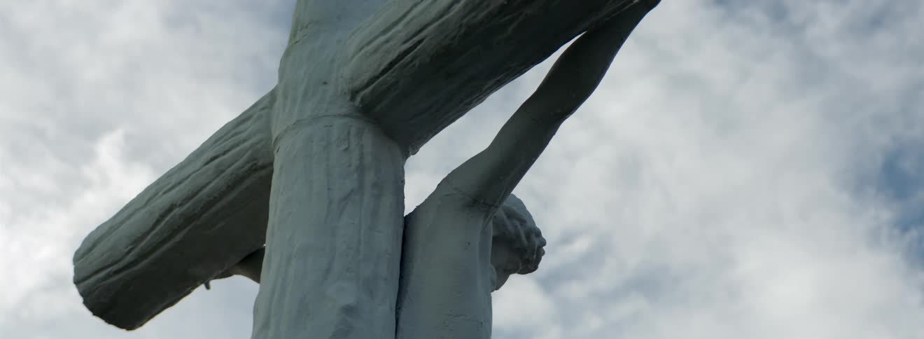 Clouds move across sky over statue of christ on the cross