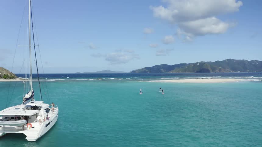 A view of the ocean with surfers and a boat with the shoreline in the distance on a sunny day