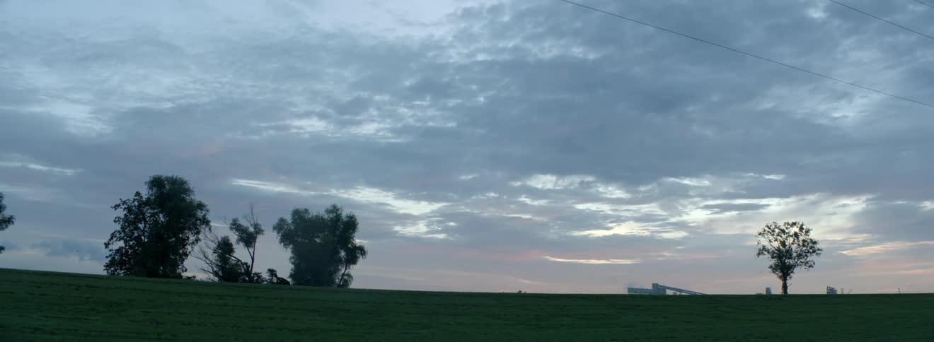 Mowed grass stretches to pink tinted horizon under cloudy sky