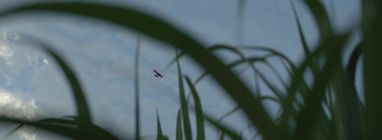A small plane is moving through a cloudy morning sky before sunrise