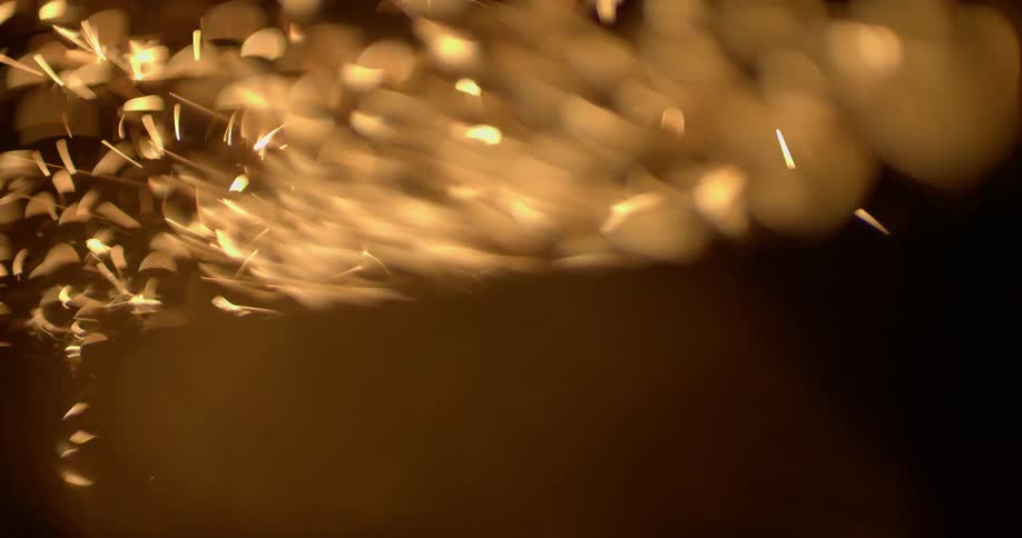 A continuous flurry of sparks are emitted upwards into the darkness