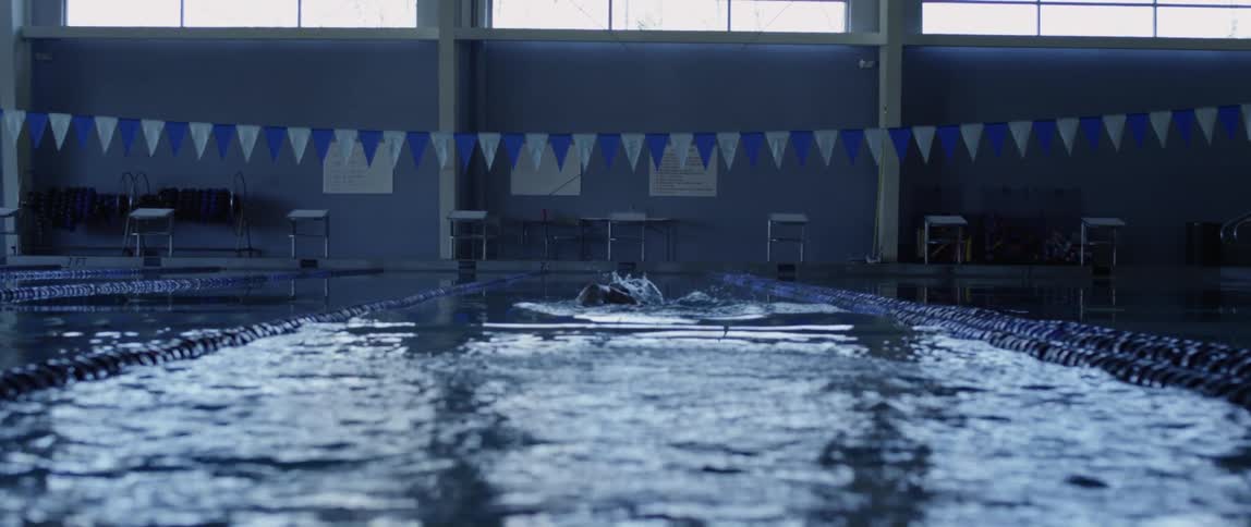 Male swim athlete swimming in an indoor pool at daytime