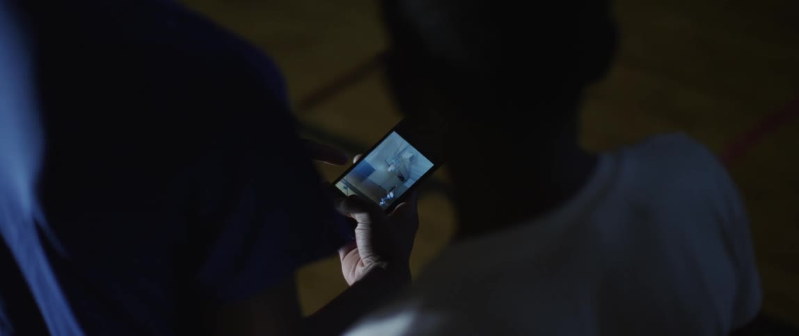 Two young boys watching a screen on a smartphone that one of them is holding in their hands