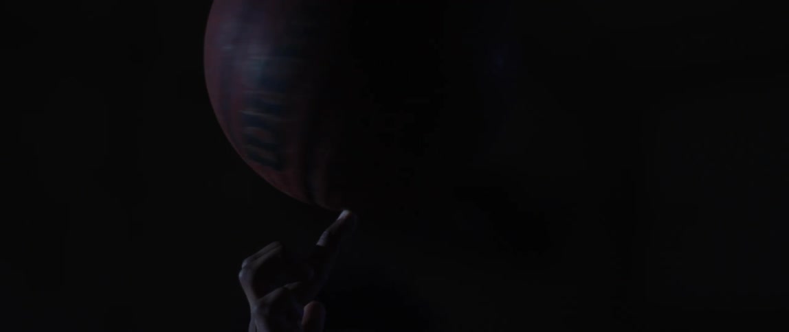 Close up of a basketball spinning on the tip of the fingers of a player in a dark room