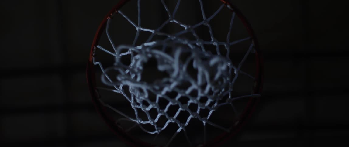 Basketball net in a pitch dark room gets a basketball throw into it
