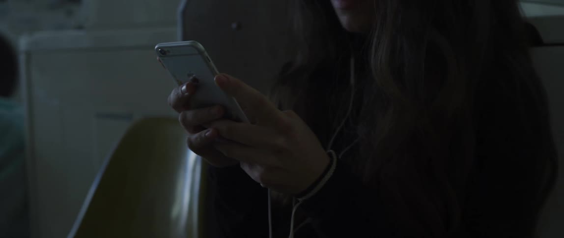 A woman is texting on a phone while sitting in a room