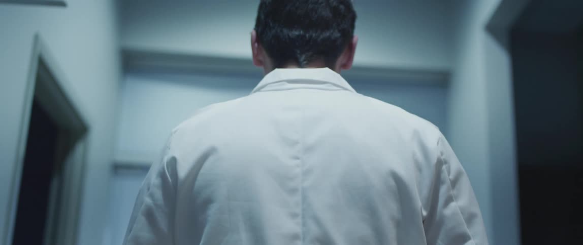 A male doctor walking in a hallway near many doorways