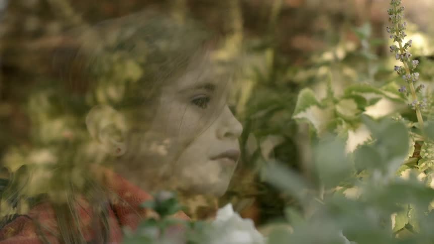 A girl is sitting behind glass looking out
