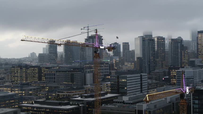 Multiple construction cranes dot the skyline above high-rise buildings
