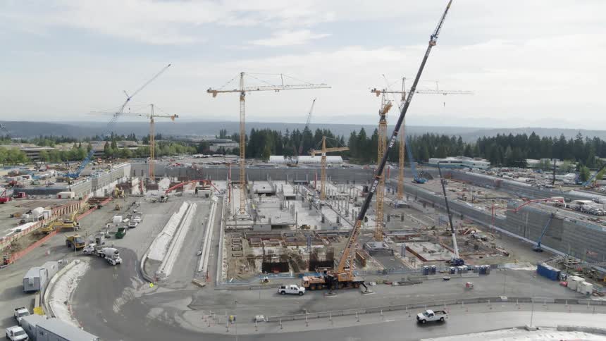Aerial traverse across an extremely large construction site bustling with activity