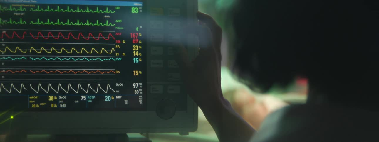 Woman pressing buttons on a heart rate monitor machine in a hospital room