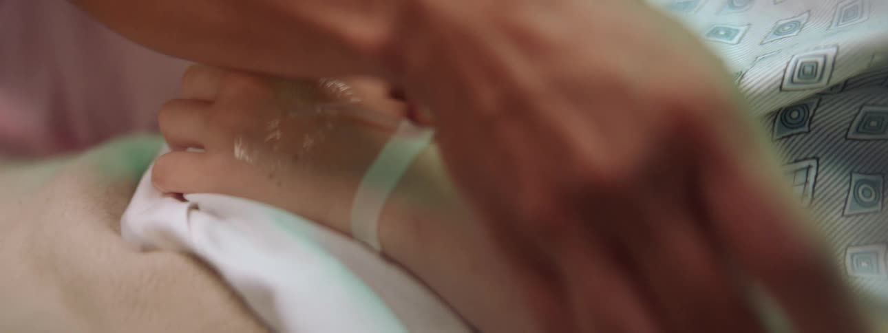 Nurse checks the intravenous fluids on an intubated patient on a bed in a hospital