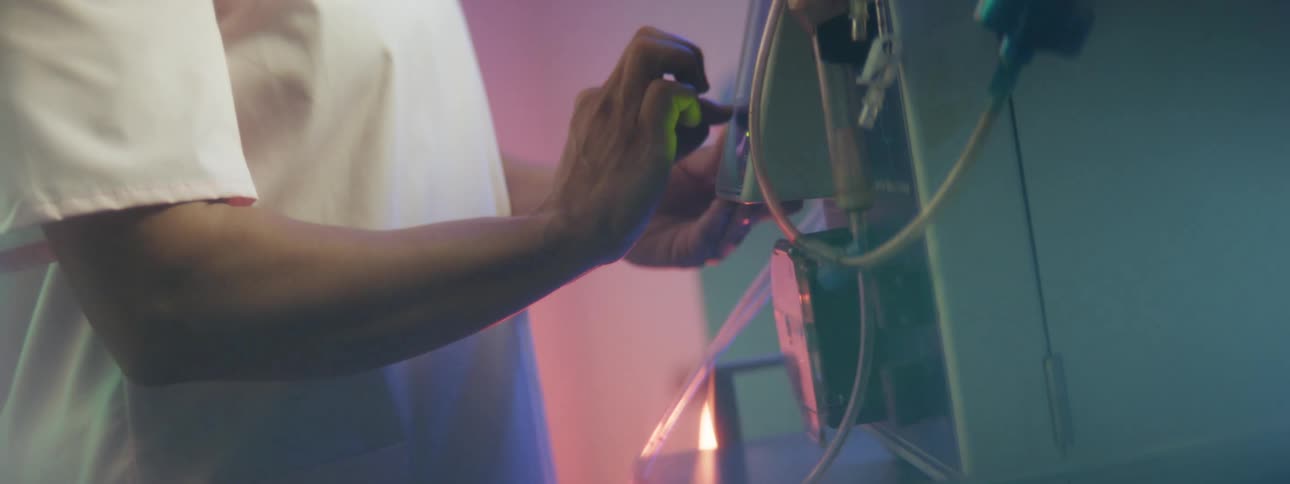 A person standing in a room touching a machine with wires