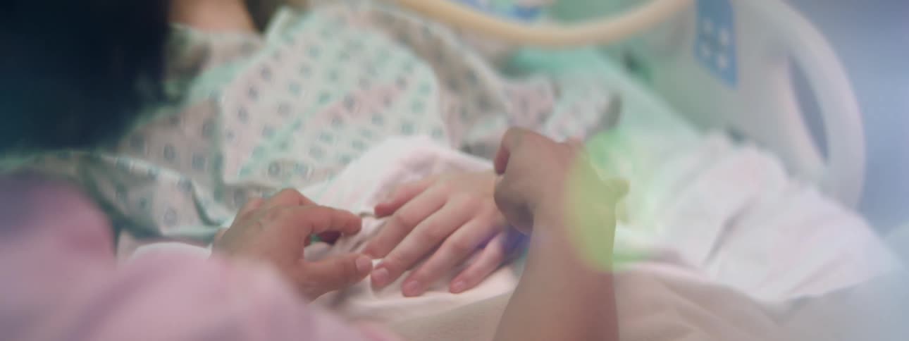 Nurse in pink scrubs adjusting the iv a patient in a hospital bed at daytime