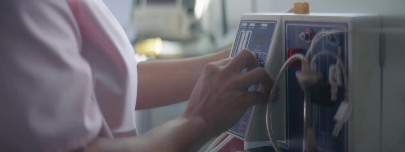 Nurse pressing buttons on medical equipment in a hospital room