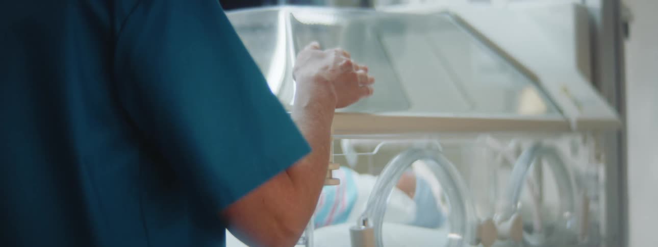 A doctor looking at a baby in an incubator