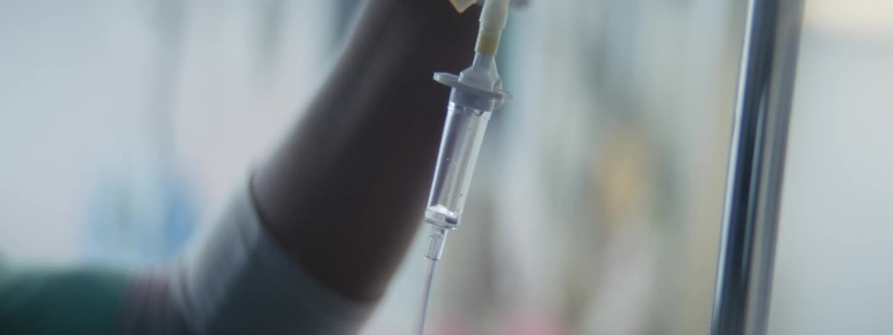 A nurse makes and adjustment to the rate of an intravenous drip