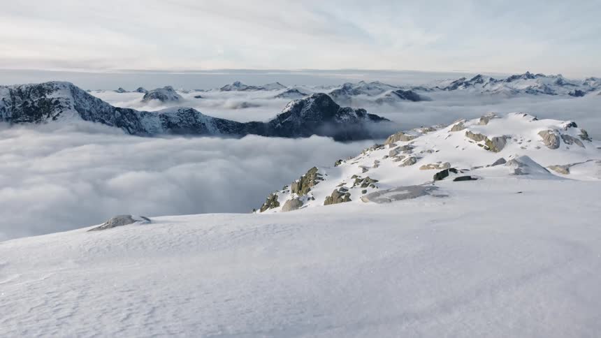 Clouds fill area between snow covered mountains stretching to horizon
