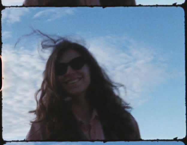 Wind blows hair into face of woman standing outside wearing shades