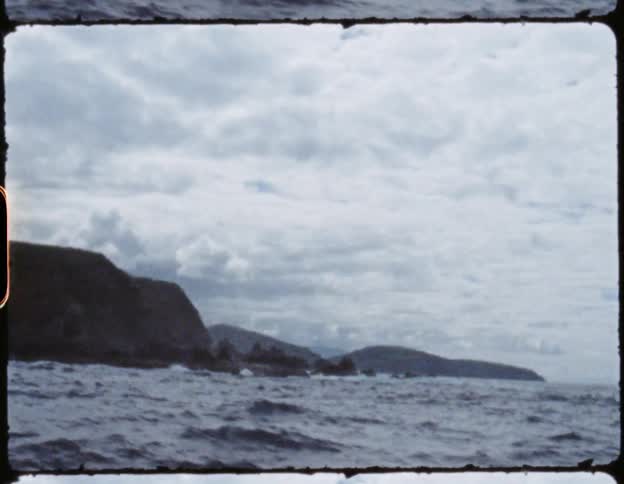A man wearing a hat and sunscreen is on a boat in the water in overcast weather